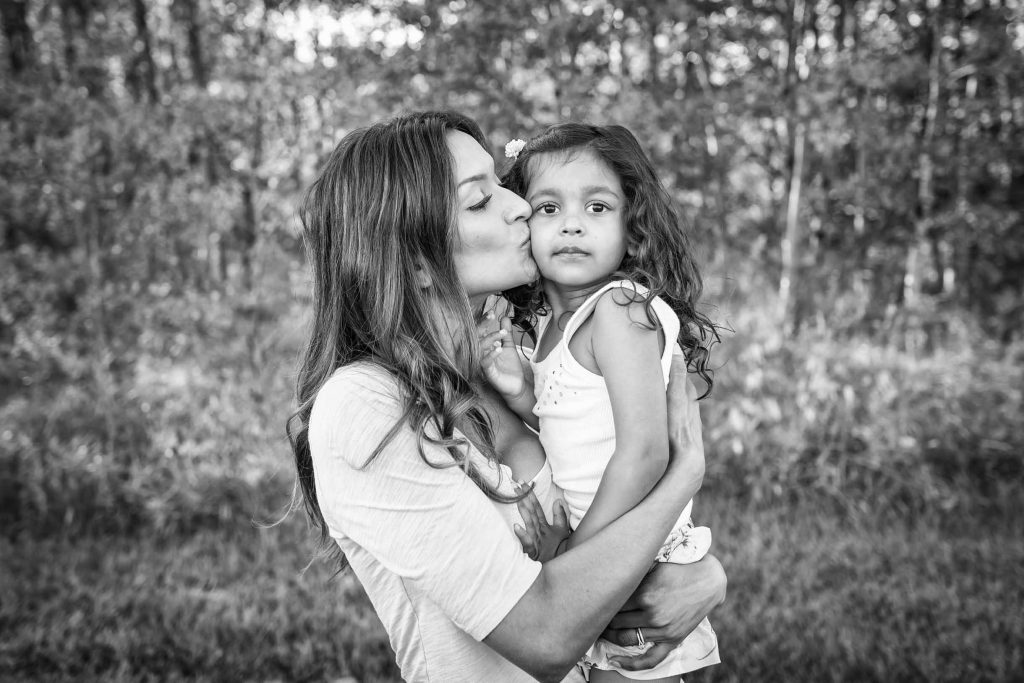 Mom kissing her daughter black and white