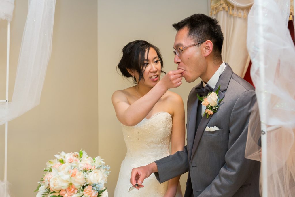 Bride and groom cut the cake and feed each other during their wedding reception