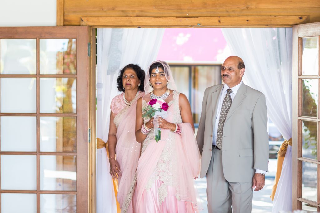 Bride being walked in by both of her parents during their Antigua destination wedding