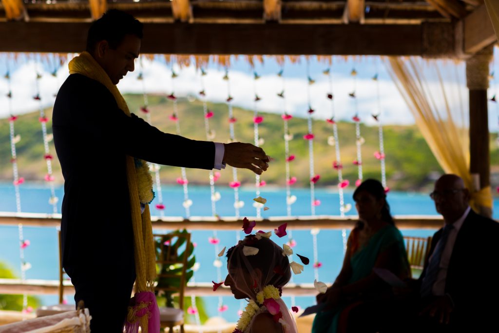 The groom showers his bride with rose petals during their romantic Antigua destination wedding