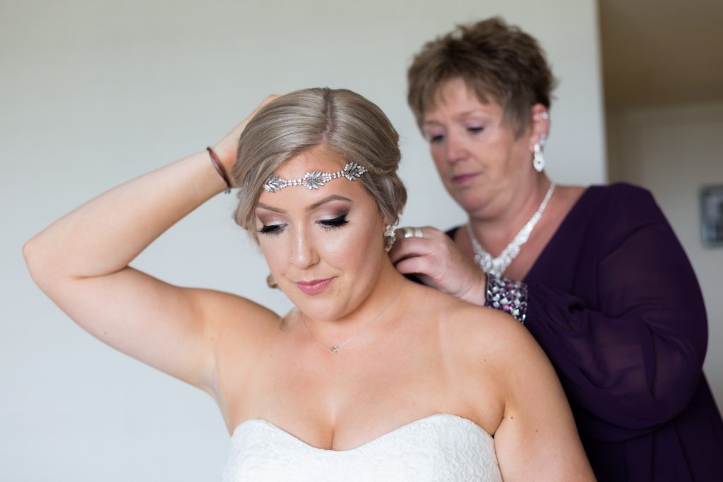 Mother of the bride helping her daughter with her jewelry before the wedding ceremony at Snow Vally
