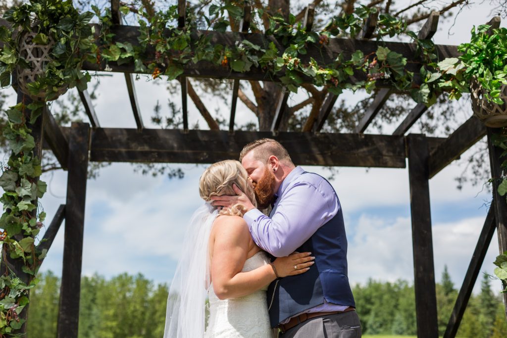 First kiss between the bride and groom during their outdoor summer wedding at Snow Valley