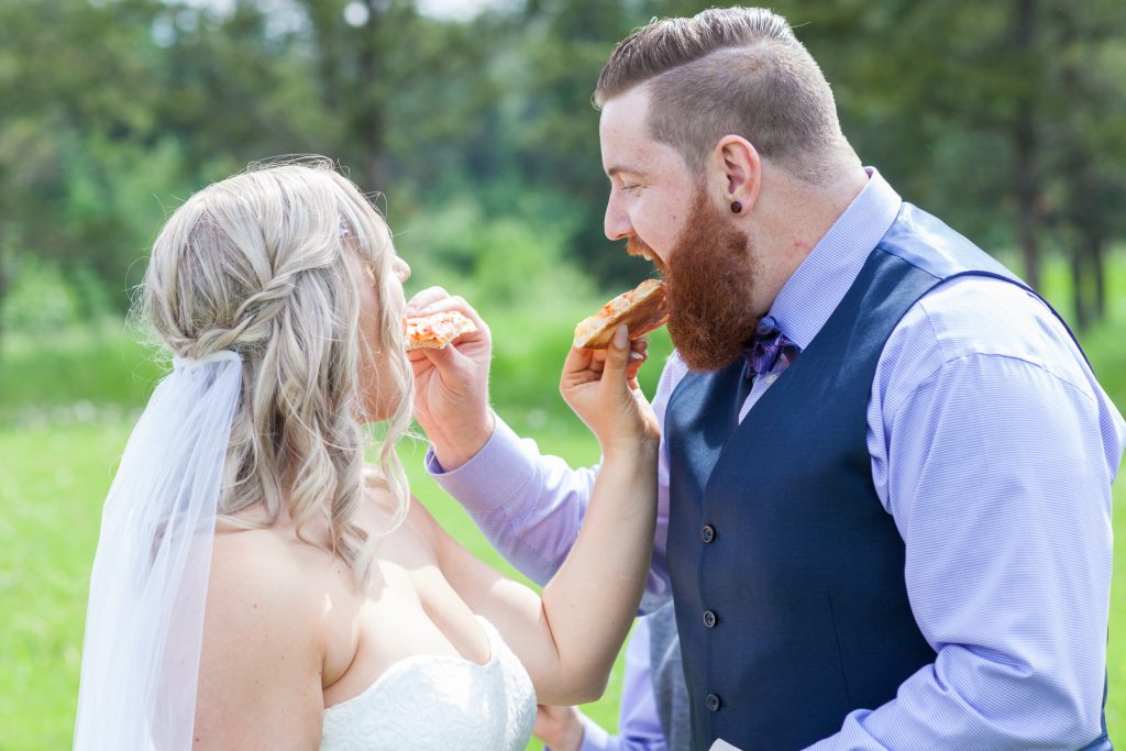 Bride and groom feed each other pizza during their portrait session at Snow Valley