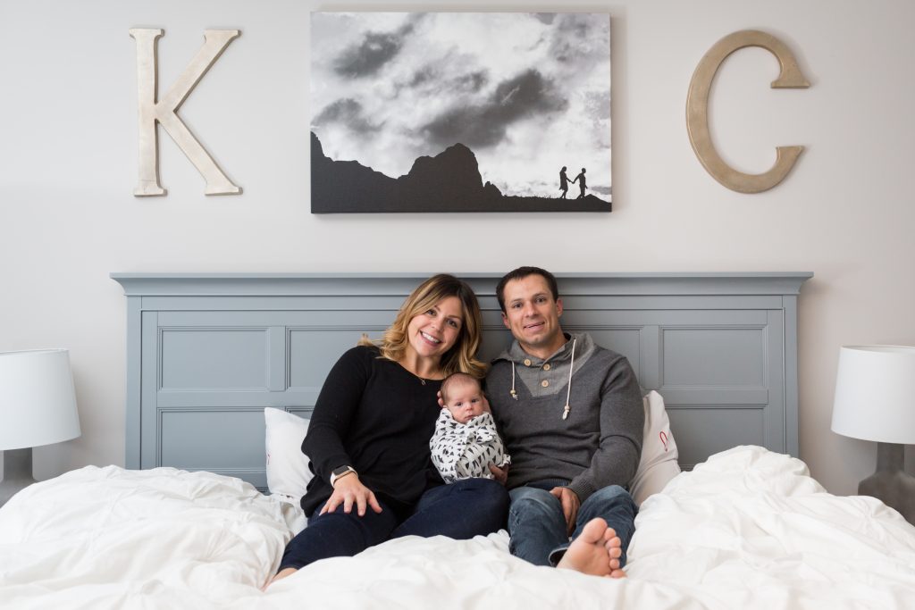 Newborn Family Portraits of parents snuggling in bed with their son